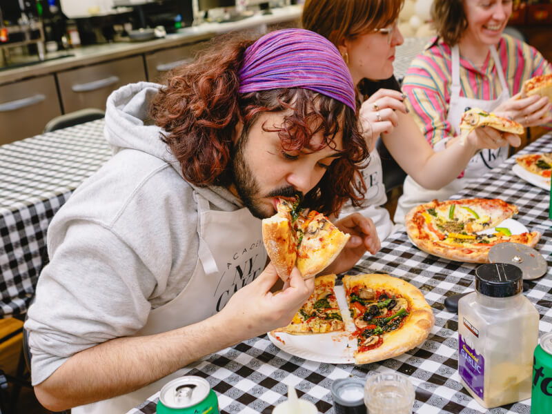 Person eating pizza in a pizza making class
